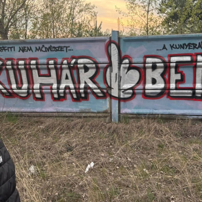 Buhár Kence pózol az őt szidó graffitivel